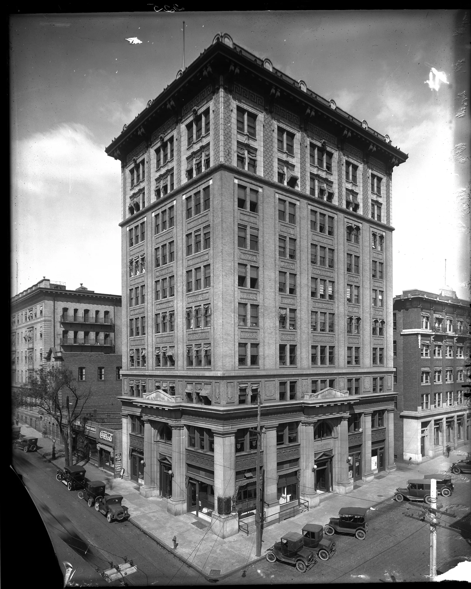 A historic photograph of downtown Richmond's commercial core in the early 1900s, showing an ornate early-skyscraper office building with Model T automobiles parked at the curb.